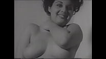 A curvy brunette with big beautiful breasts smiles at you cutely with a black and white porn video