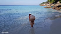 Голая рыжеволосая девушка купается на общественном пляже